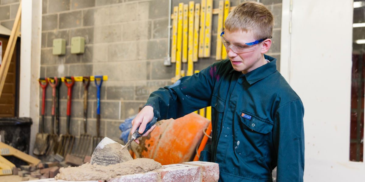 Construction Student Laying Bricks In Workshop