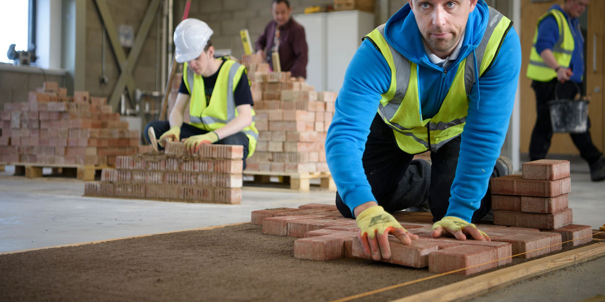 Close up photo of two male HNC Landscape Management students working with bricks / bricklaying 