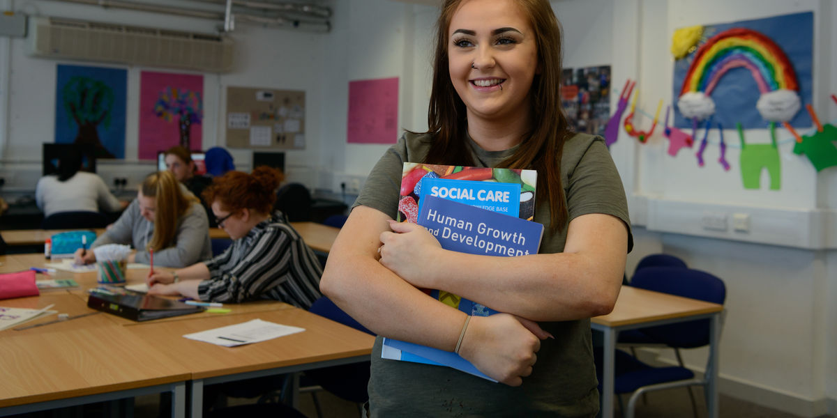 Social Care Level 5 student with book Brunette Image 4