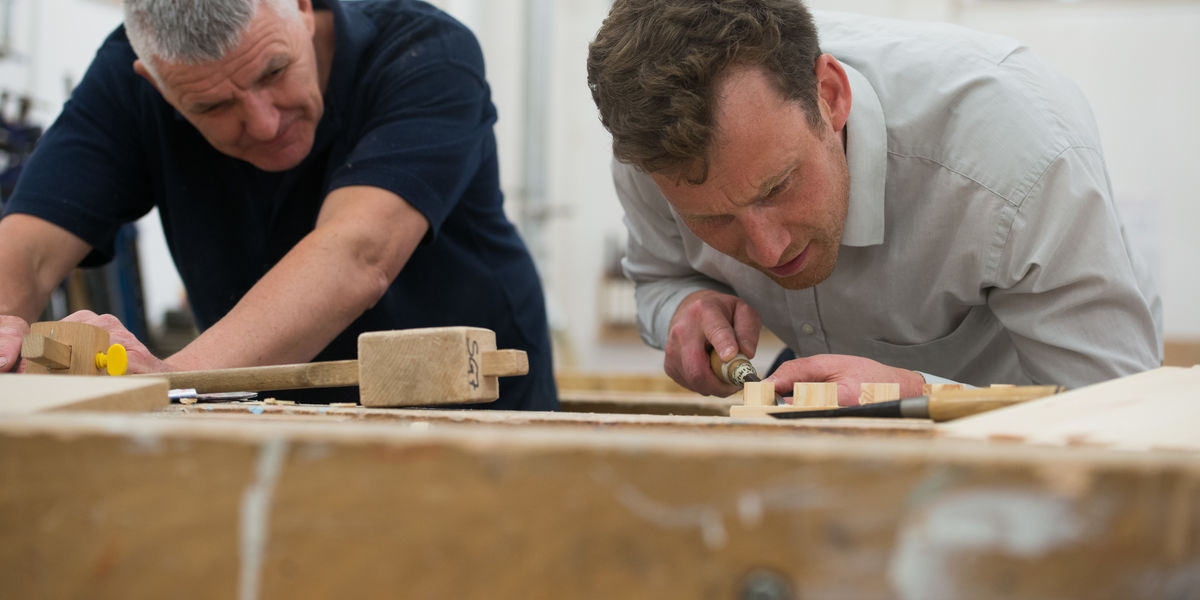 Close up of student and lecturer in woodwork