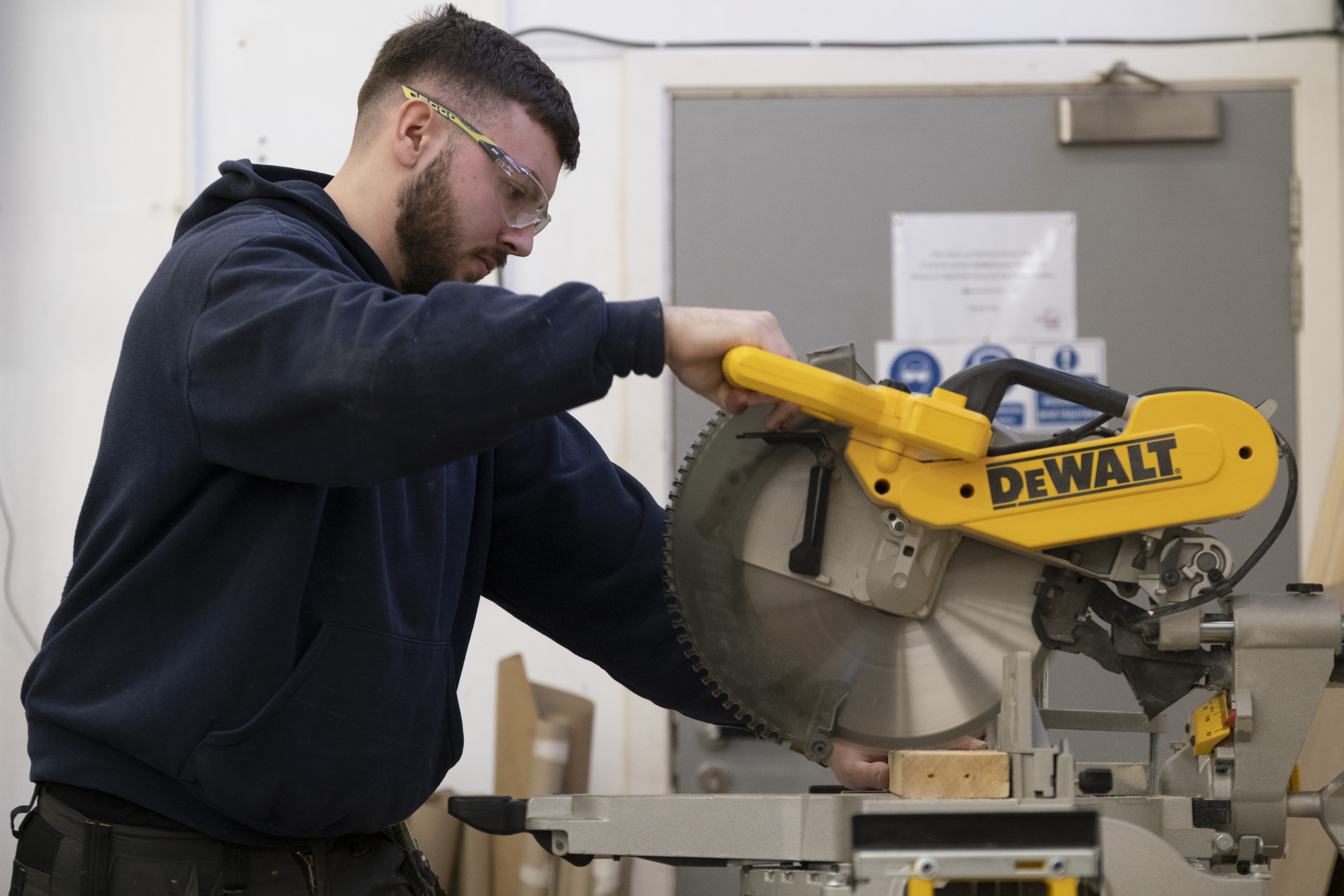 Male construction student working with electric saw