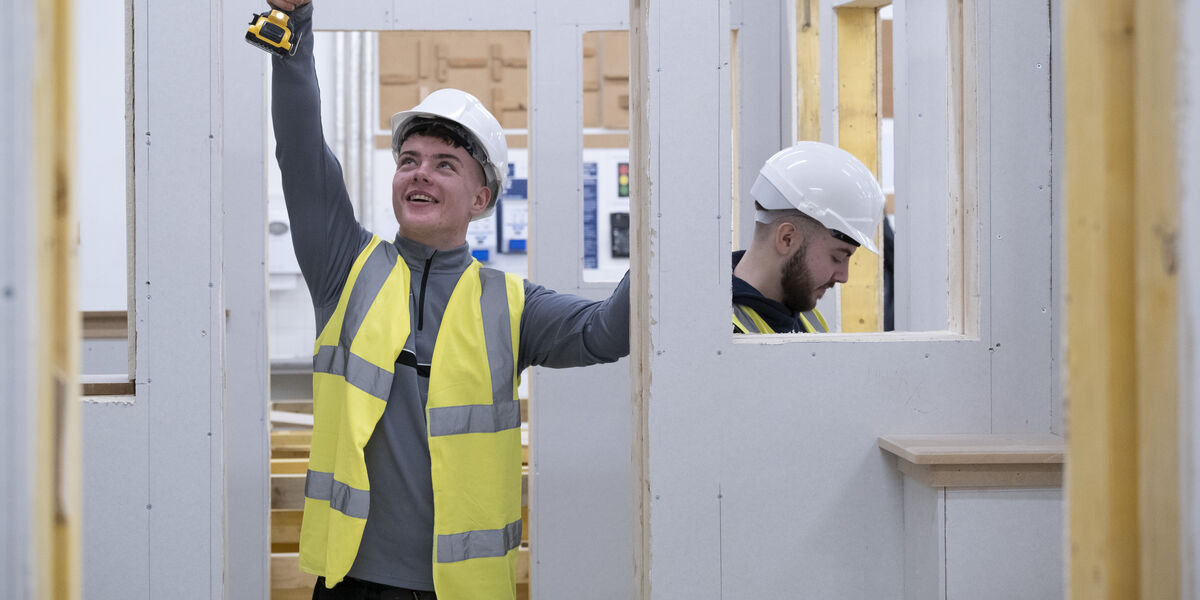 Male construction student drilling in a doorway