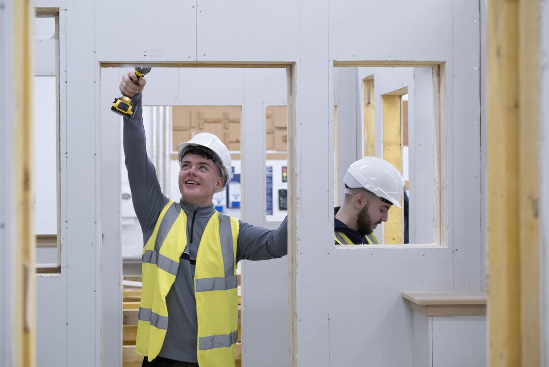 Male construction student drilling in a doorway gallery