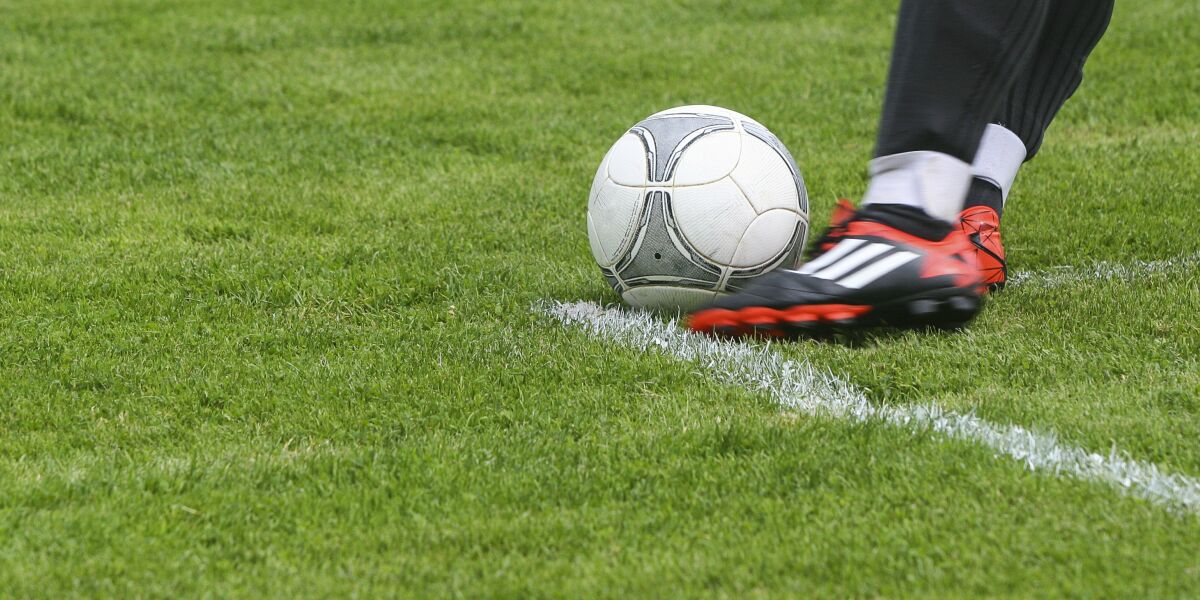 A football player kicking the ball at the edge of the box.