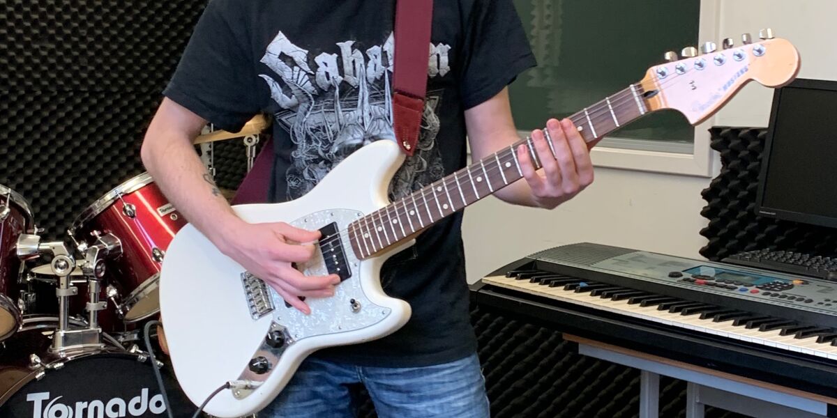 Music student playing the electric guitar in sound studio