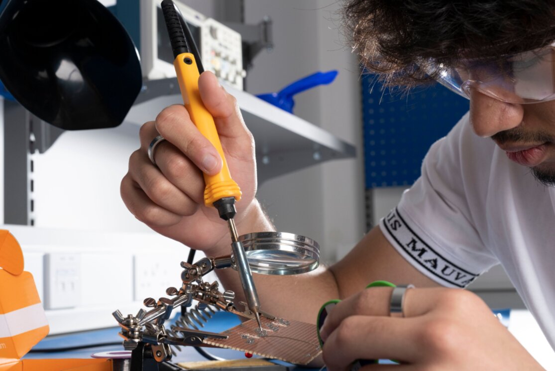 Male student working with soldering iron