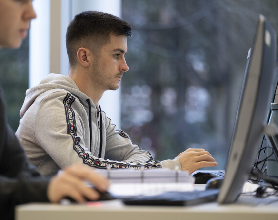male IT student sitting by a computer