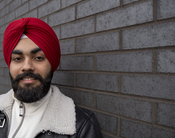 student standing by a brick wall