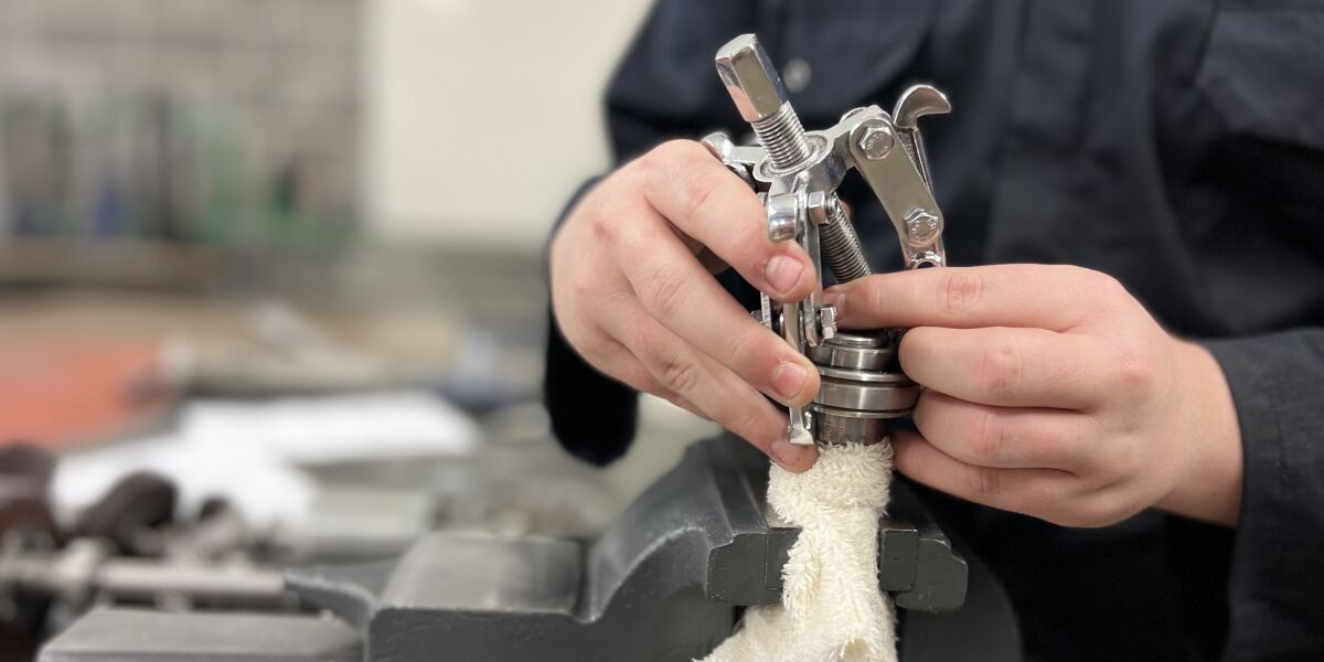 Students hands working with metal tools and clamp in workshop
