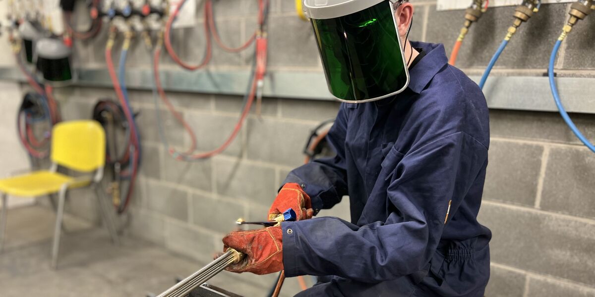 Student welding metal during class