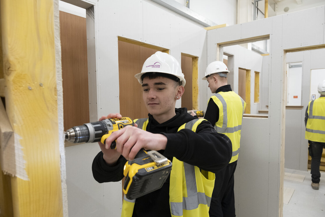 Male construction student using a drill gallery