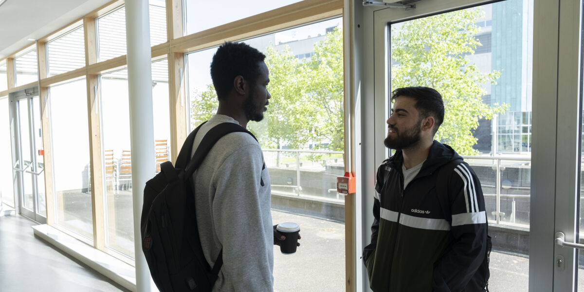 Two students chatting in a glass corridor of Anniesland Campus Glasgow Clyde College