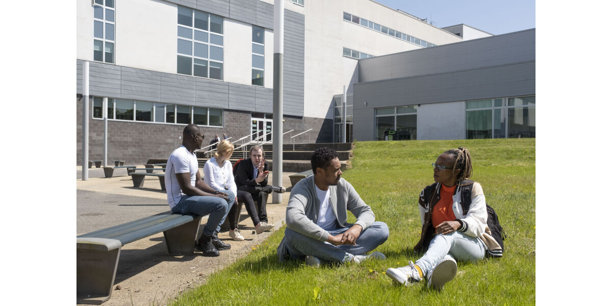 A group of male and female students sitting outside at Anniesland Campus