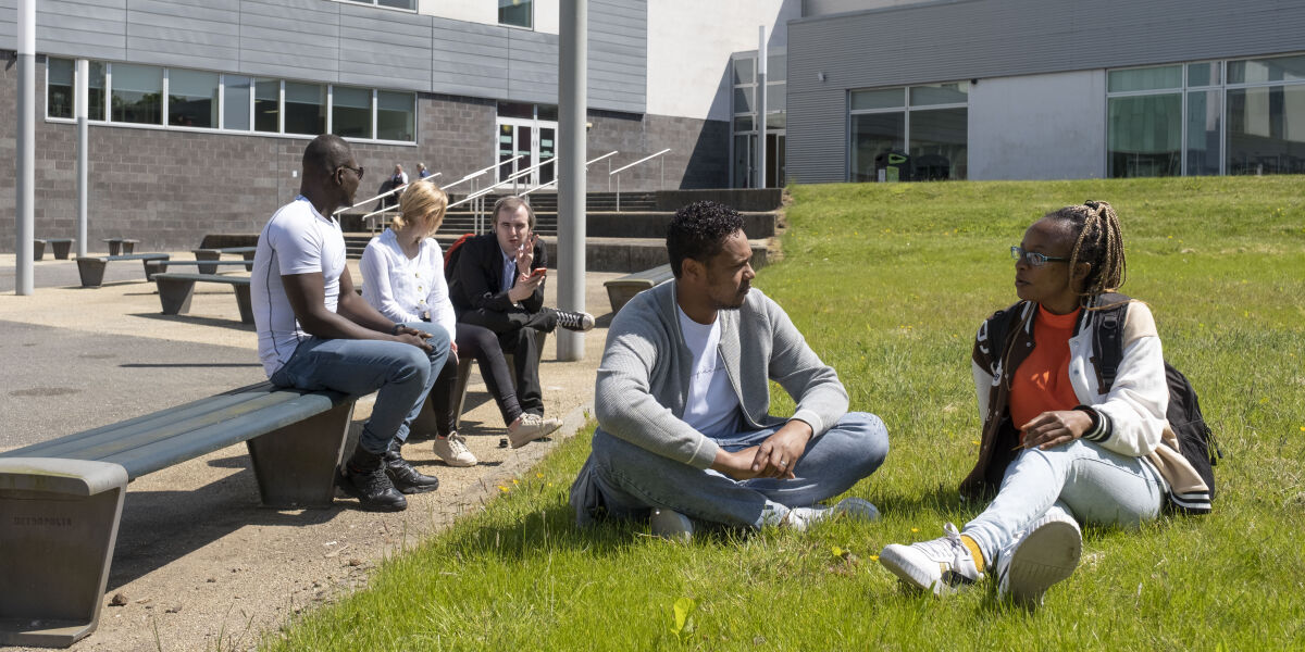 A group of male and female students sitting outside at Anniesland Campus
