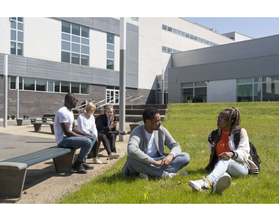A group of male and female students sitting outside at Anniesland Campus