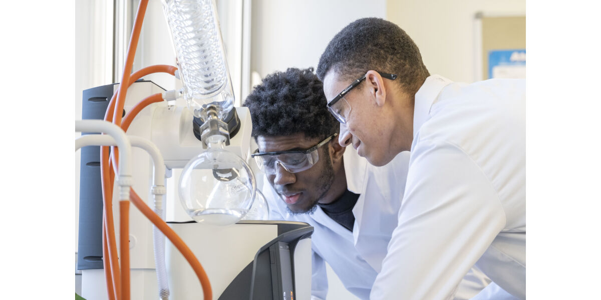 Two science students undertaking an experiment wearing white lab coats. 