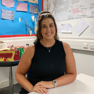 Rebecca Swift- HNC Childhood Practice student sitting in an early education classroom smiling at the camera.