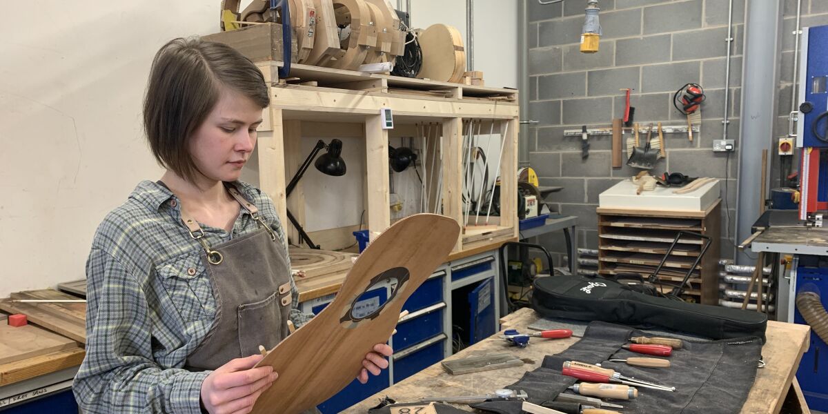 Stringed instrument making student with guitar