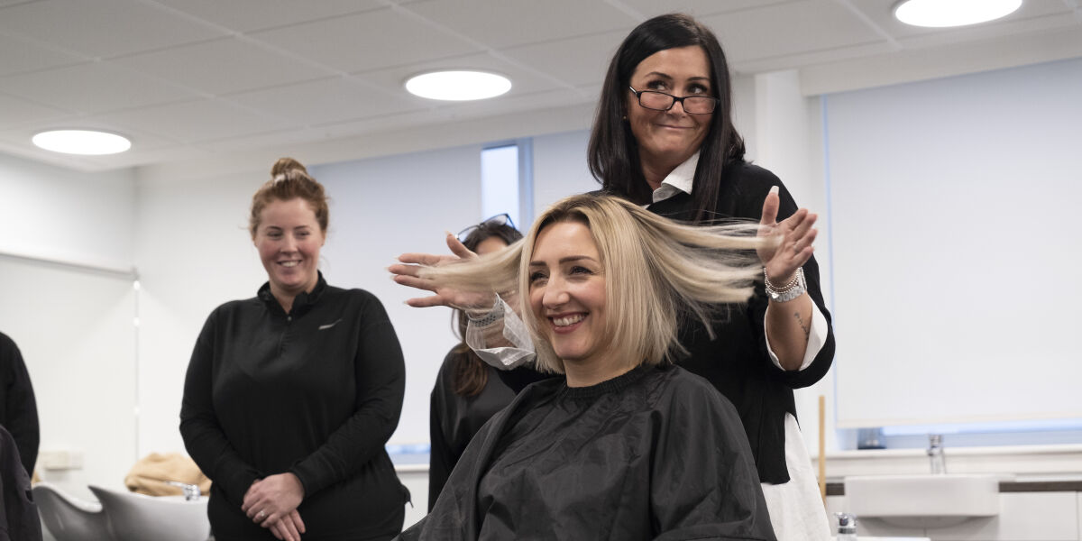 Hair stylist checking the length of their model's hair. 