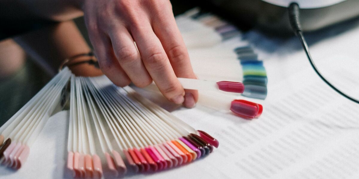 Nail technician choosing a colour of nail varnish for a client from the set of colour samples.