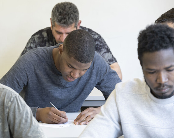 A group of male students taking notes at their desks
