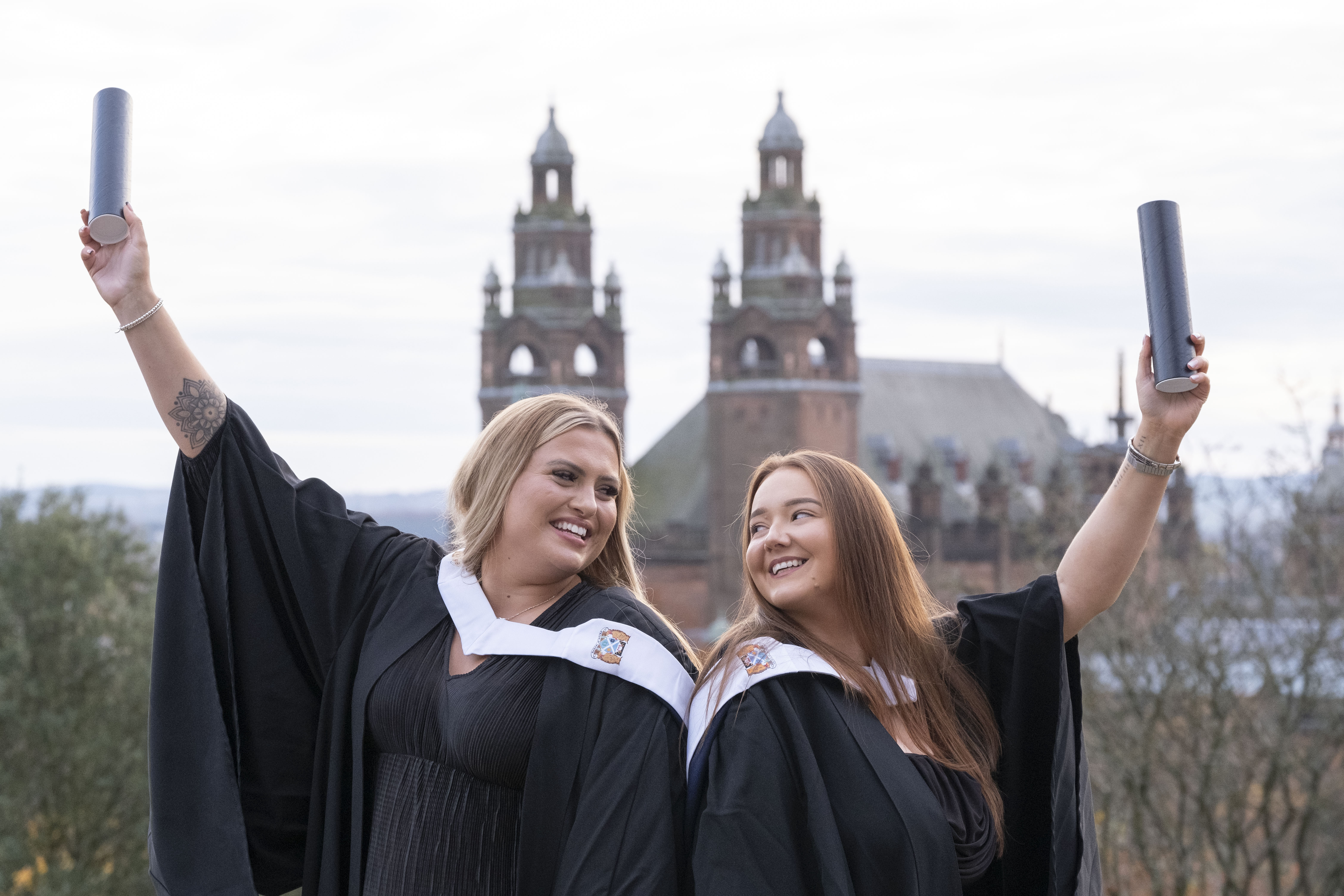 Two female graduates holding their scrolls