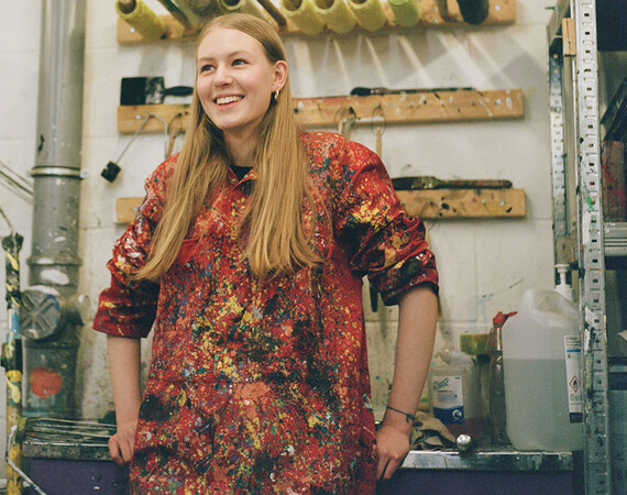 Female student in art with paint splattered overalls