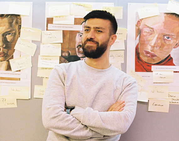 Male student in Anniesland corridor with artwork behind him