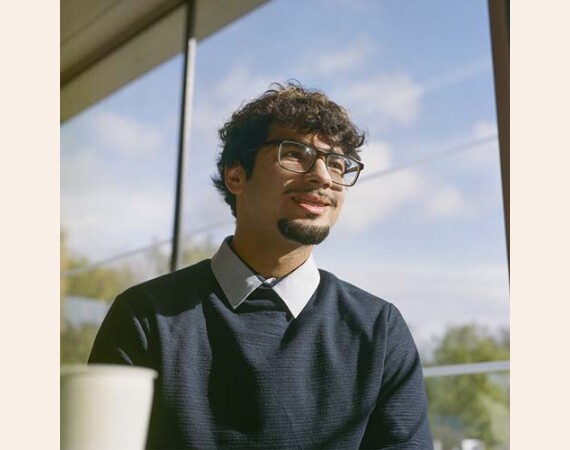 Male student with glasses by window in Cardonald Canteen