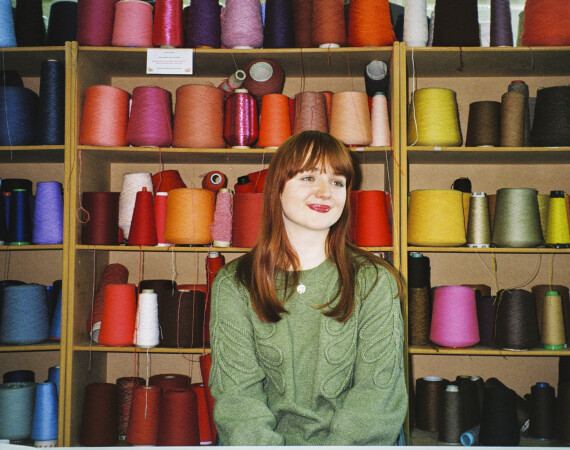 Female fashion student standing in front of colourful rolls of wool