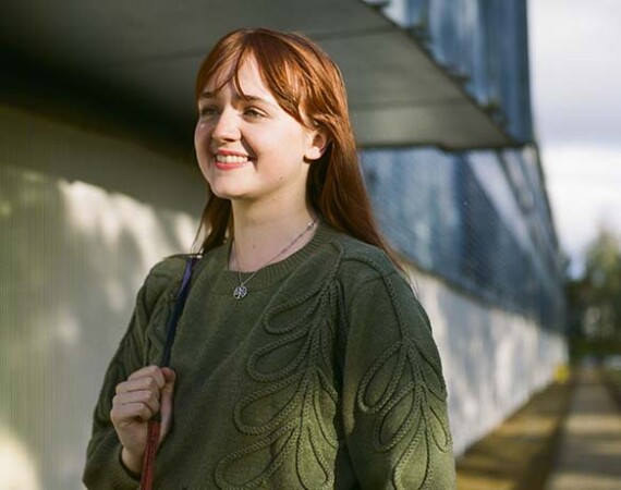 Female student outside Cardonald Campus wearing green jumper.