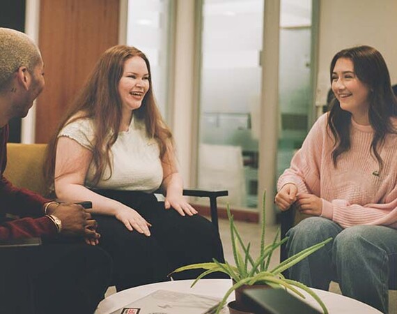 Mixed group of students chatting in seating area at Langside Campus