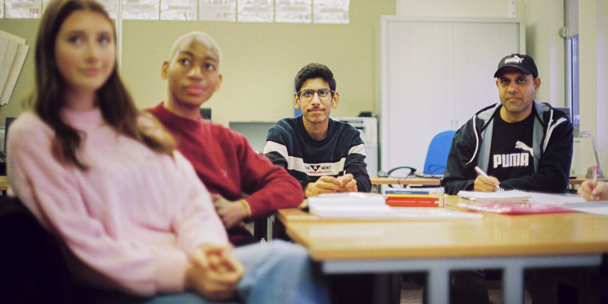 Group of male and female students at desk in classroom