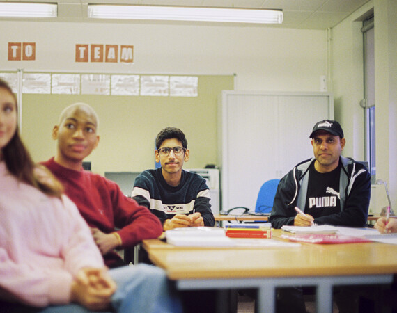 Group of male and female students at desk in classroom