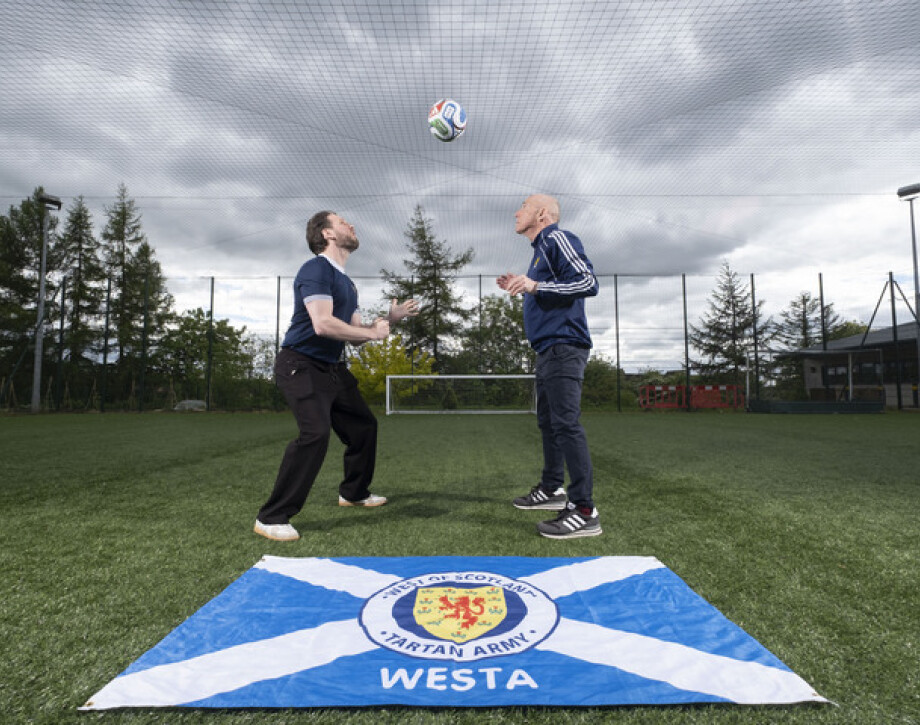 Image shows Glasgow Clyde College World Cup Masterclass hosts Craig Telfer and Hamish Husband with Scotland flag.
