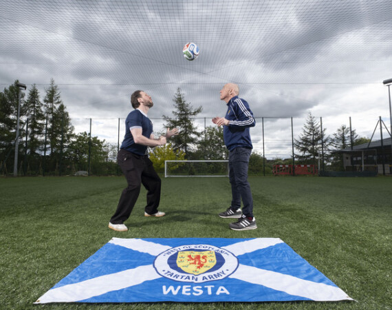 Image shows Glasgow Clyde College World Cup Masterclass hosts Craig Telfer and Hamish Husband with Scotland flag.