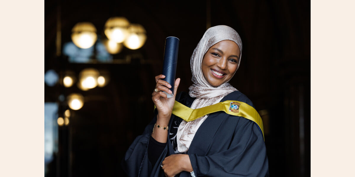Image shows Female graduate at Glasgow Clyde College graduation 2025 holding a scroll up