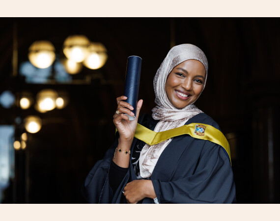 Image shows Female graduate at Glasgow Clyde College graduation 2025 holding a scroll up