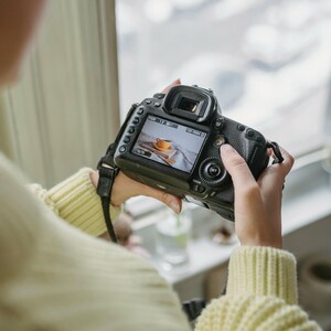 A female holding a camera and checking the image on the camera screen. 